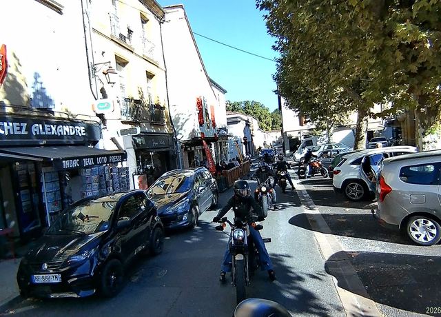 Traversée de village, le cortège au pas devant les terrasses.
